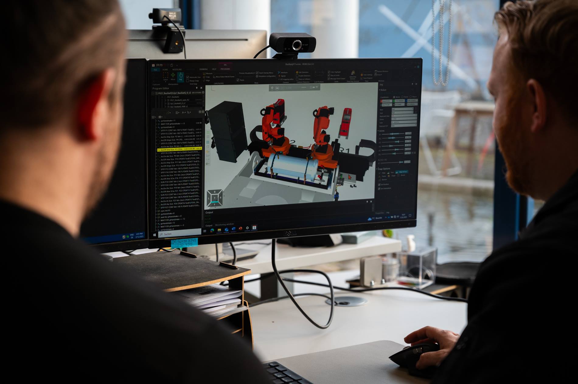 Zwei Mitarbeiter von HASE Kaminofenbau GmbH programmieren Offline-Simulation am Computer.