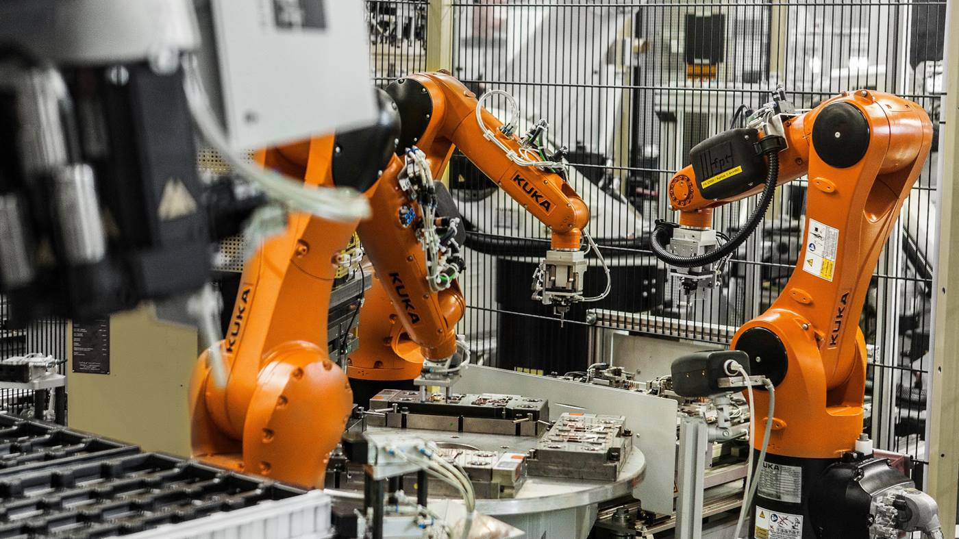 KUKA Roboter nimmt mit speziellen Greifer aufbereitete Rohteile aus übergabeschieber und legt sie in Spritzgussmaschine