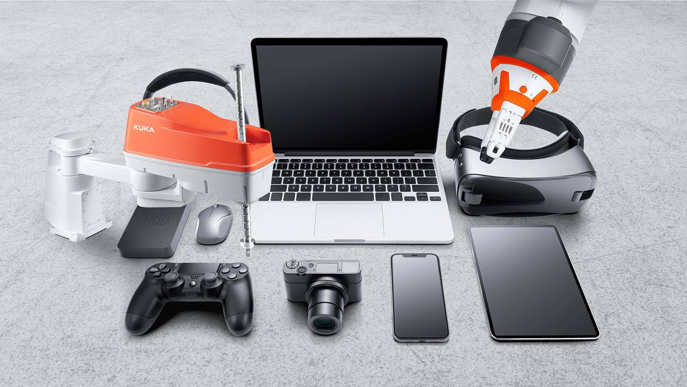 Verschiedene Ger?te der Unterhaltungselektronik - Laptop, Smartphonw, Spielkonsole, Tablet, Kopfh?rer, externe Festplatte, Maus, VR-Brille - und zwei KUKA Roboter