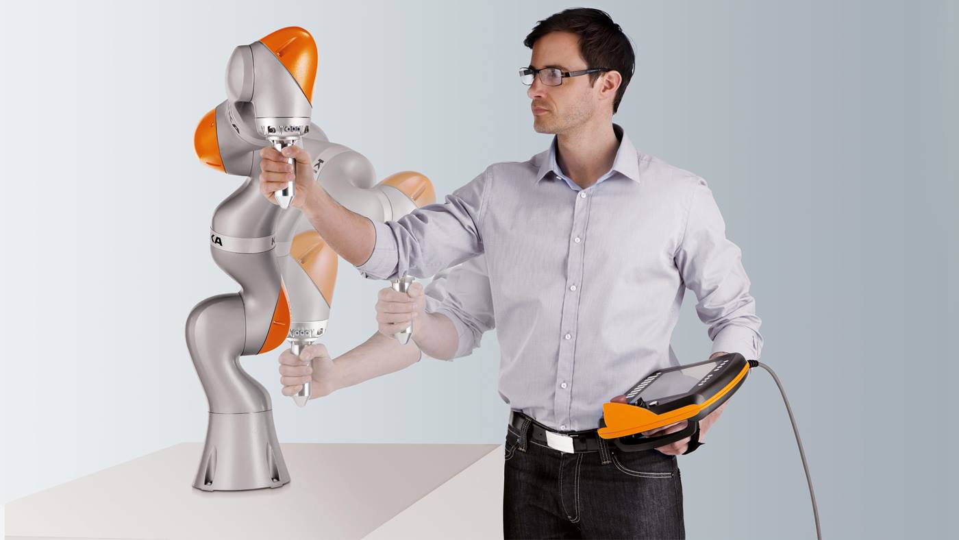 A human teaches the LBR iiwa movements by demonstrating.